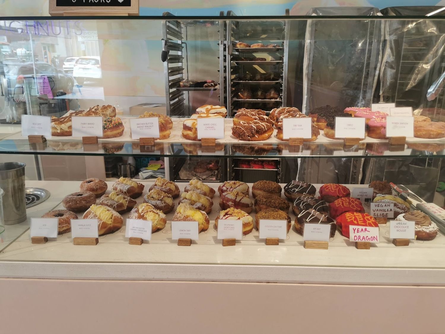The Circle of Life doughnut case, with labelled flavours and the cloud mural above